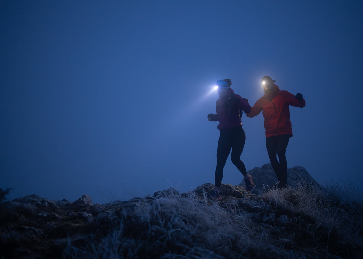 Two people on a mountain top at night with headlamps